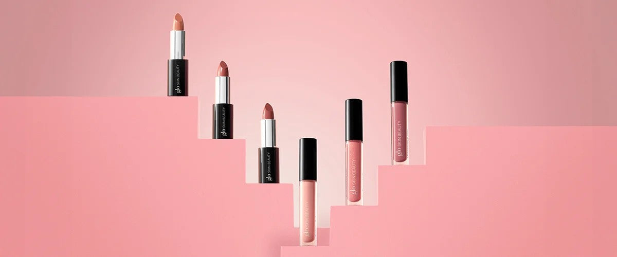 Three lipsticks and three glosses arranged on pink stepped platforms; packaging labeled 'Glo Skin Beauty'.