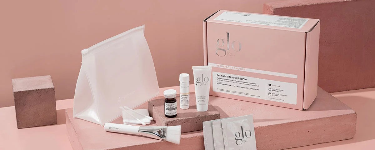 glo Resurface + Smooth Retinol + C Smoothing Peel — pink box with tubes, sachets, brush and pouch on pink blocks