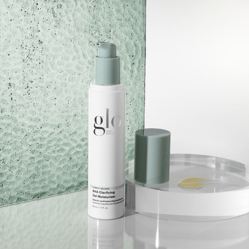 White pump bottle labeled 'glo' 'SKIN BEAUTY' and 'BHA Clarifying Gel Moisturizer' with green cap beside a clear tray