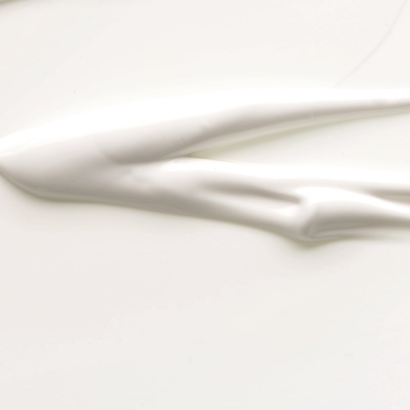 Thick white cream smeared in a smooth streak across a pale surface