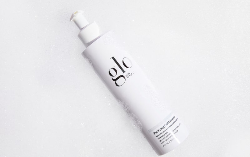 glo skin beauty bottle labeled Purifying Gel Cleanser resting in foam