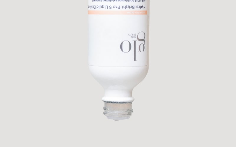 Upside-down glo SKIN BEAUTY bottle labeled Hydra-bright Pro 5 Liquid Exfoliant with a drop at the opening