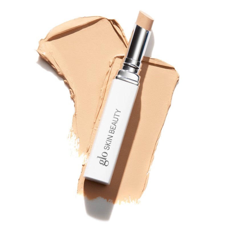 Glo Skin Beauty concealer stick labeled 'glo SKIN BEAUTY' on two beige makeup swatches