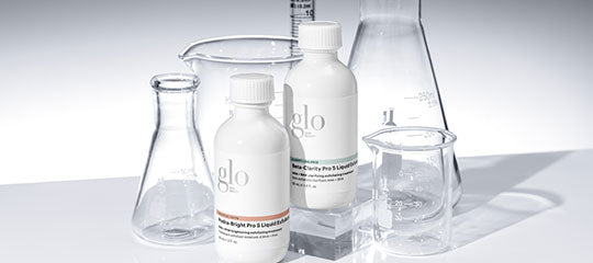 Laboratory glassware (Erlenmeyer flask, beaker, graduated cylinder) with two white bottles labeled 'glo' on a white surface