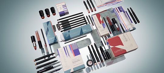 Flat lay of Glo Skin Beauty holiday makeup kits showing boxed palettes, lipsticks, liners, and pencils on a pale backdrop