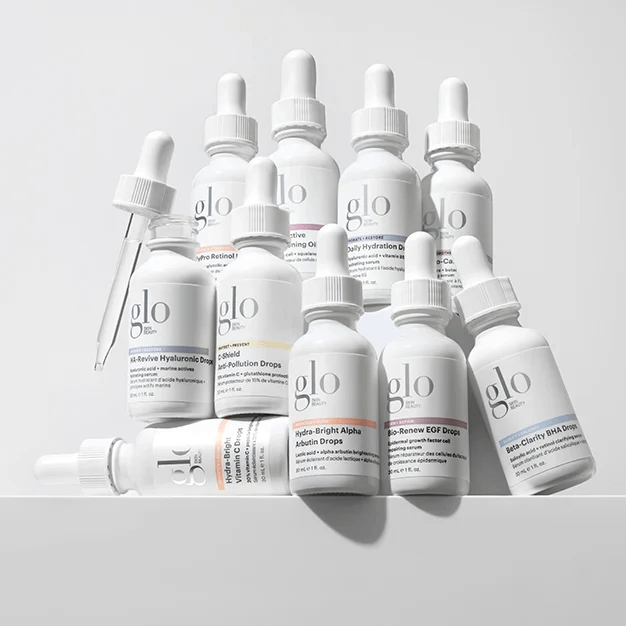 Group of white glo skincare dropper bottles and a pipette, assorted serum labels visible