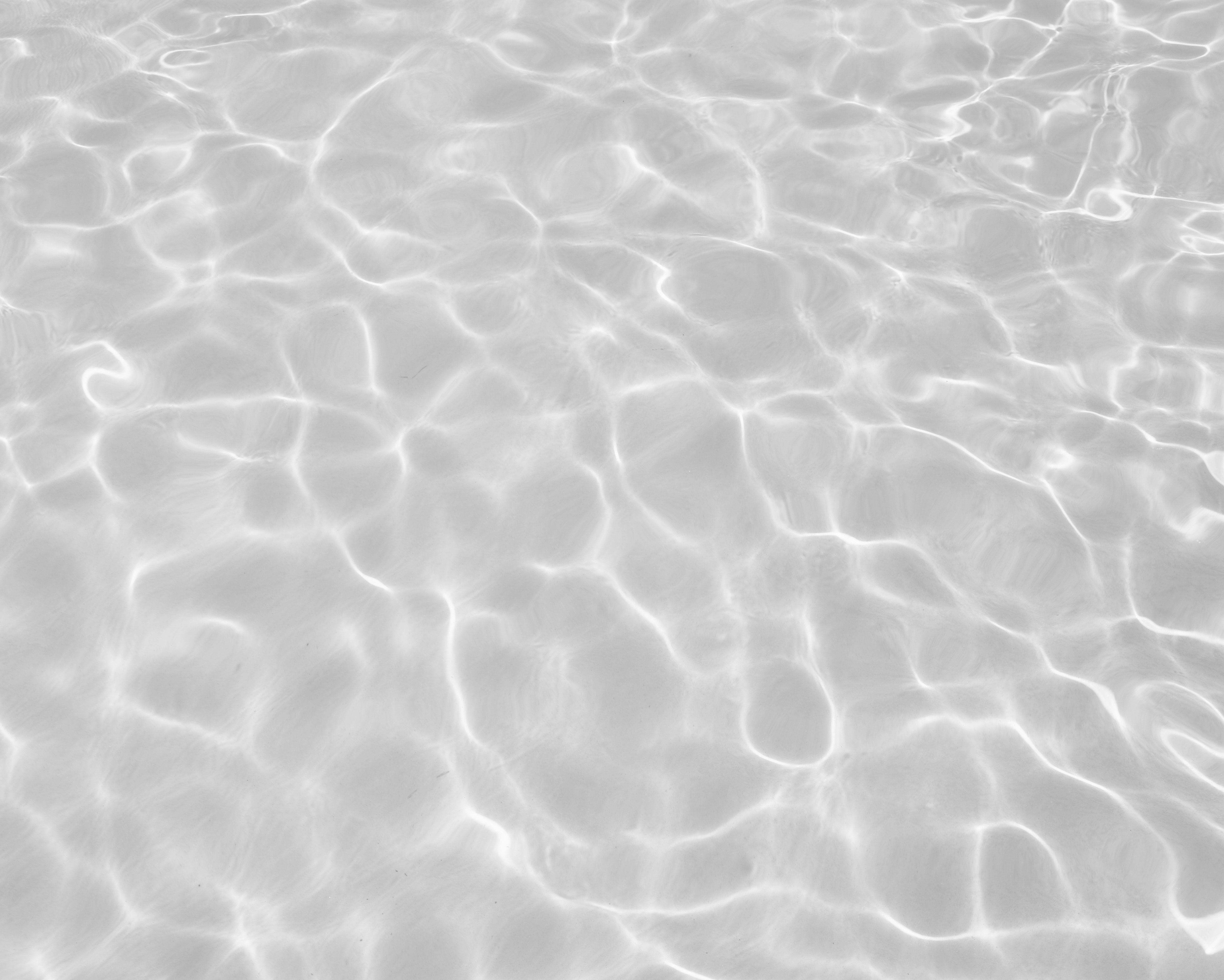 Sunlit shallow water with shimmering ripple patterns and bright caustic reflections