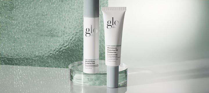 Glo skincare display: tube labeled 'glo' with 'Microbiome Restoring PM Moisturizer' and a glo pump bottle on a glass pedestal.