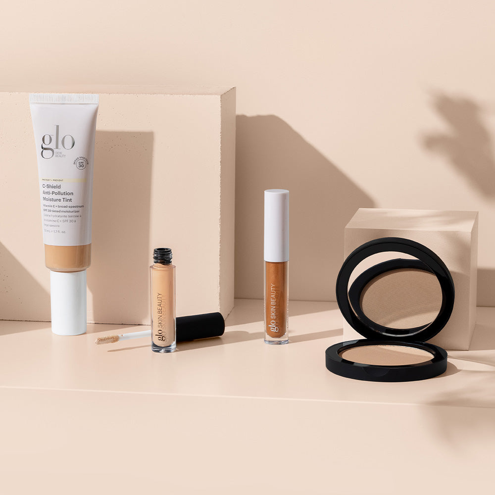 glo SKIN BEAUTY C-Shield Anti-Pollution Moisture Tint SPF 30 tube with two liquid tints and open compact on beige blocks