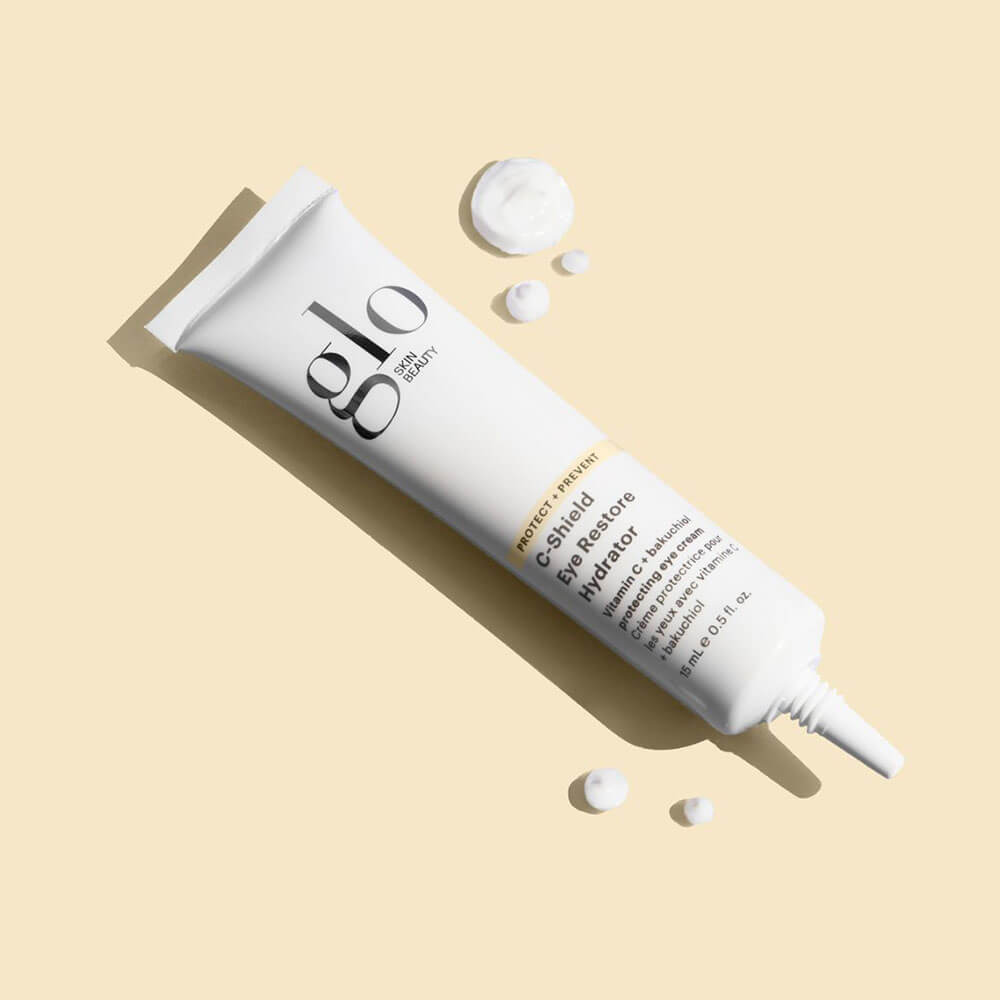 White Glo Skin Beauty C-Shield Eye Restore Hydrator tube on pale beige background with three dollops of cream