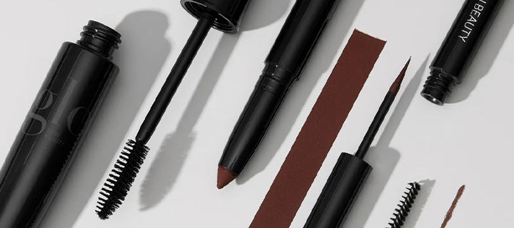 Black mascara and eyeliner tools laid out with a brown color swatch; tube labeled BEAUTY