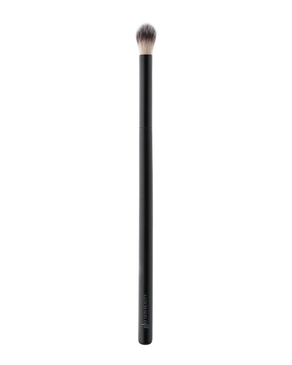 Small rounded detail blending makeup brush with black handle labeled glo SKIN BEAUTY