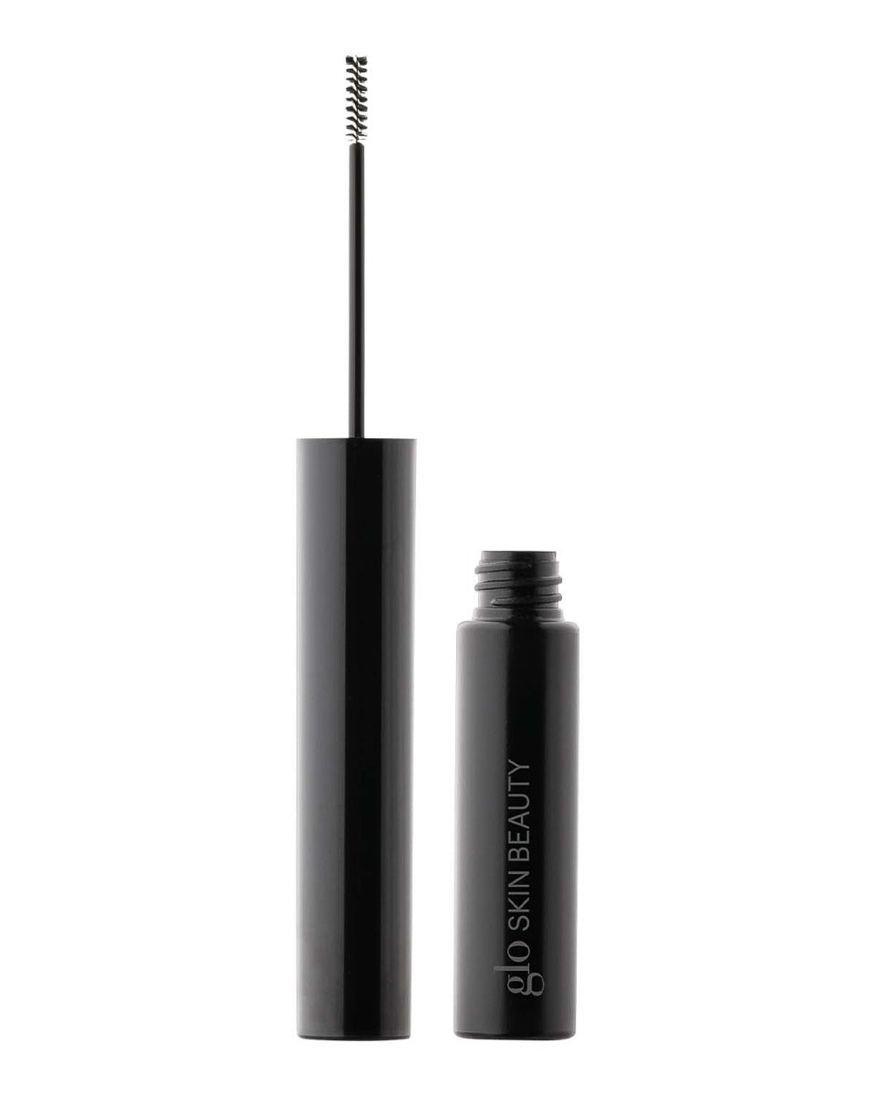 Open black brow gel tube with thin spoolie wand; bottle labeled 'glo SKIN BEAUTY'.