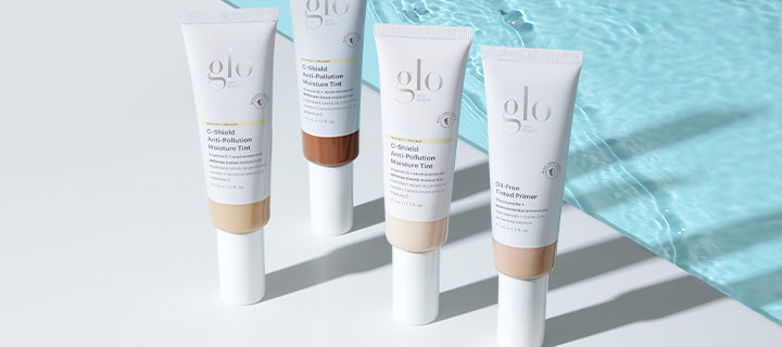 Four glo tubes on a tabletop by pool; labels read 'C-Shield Anti-Pollution Moisture Tint' and 'Oil-Free Tinted Primer'.