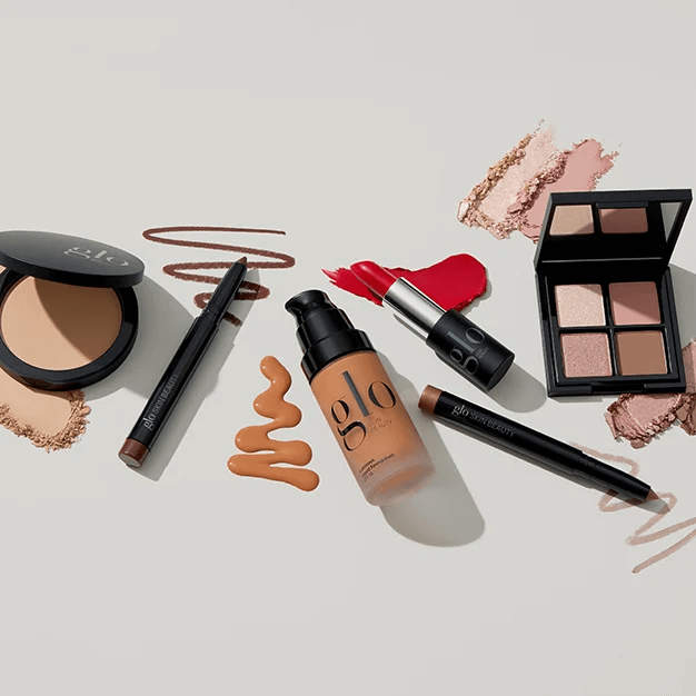 Assortment of glo and glo skin beauty makeup: liquid foundation pump, red lipstick, eyeshadow quad, compact powder, liner pencils and swatches