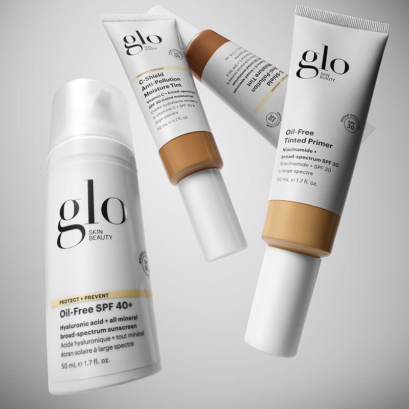 Angled view of Glo Skin Beauty oil-free SPF 40+ pump and two tinted primers showing shade and packaging on light gray background