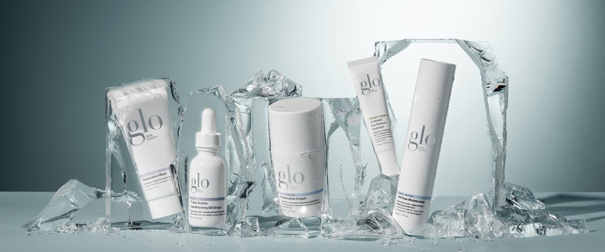 Glo Skin Beauty skincare lineup—serum, cream, moisturizer and mask displayed among ice blocks.