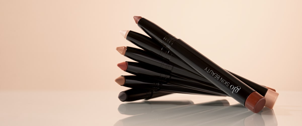 Stacked neutral-toned cream eye-pencil sticks with visible branding reading Glo Skin Beauty