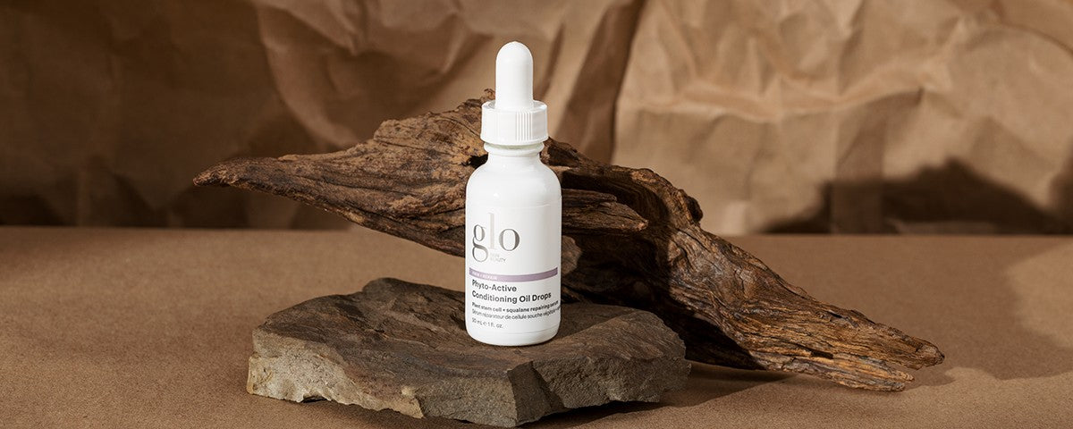 glo Phyto-Active Conditioning Oil Drops bottle on stone with driftwood backdrop