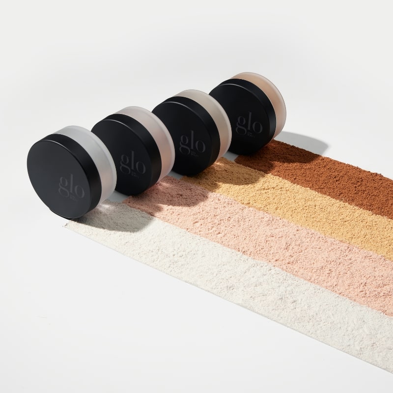Line of four glo setting powder jars with five powder swatches ranging from light to deep