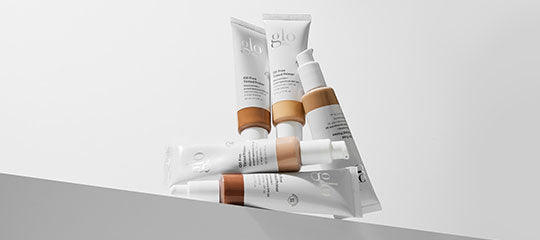 Stacked glo skincare tubes in varying foundation shades on an angled white surface