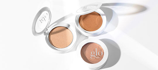 Three open compact powder bronzers in white cases with glo logo, warm beige and bronze shades
