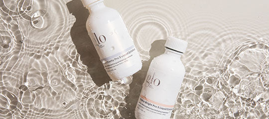 Two white glo skincare bottles floating in rippled water, angled with visible 'glo' logo on labels.