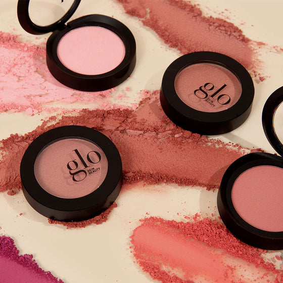Three pink powder blush compacts and crushed swatches; one compact labeled glo SKIN BEAUTY