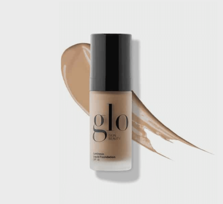 Bottle of glo Skin Beauty Luminous Liquid Foundation with beige foundation swatch and black cap