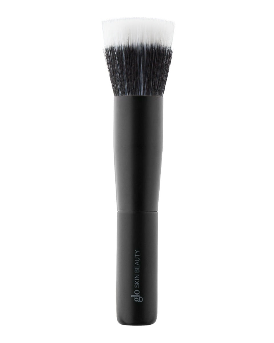Front view of mini dual-fiber cheek brush showcasing two-tone dense bristles and short matte black handle on white background